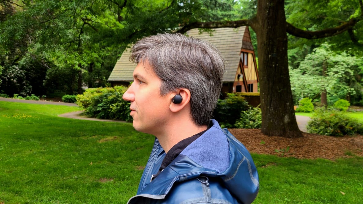 一个英俊的男人戴着一副真正的无线耳机，置身于大自然的庄严之中