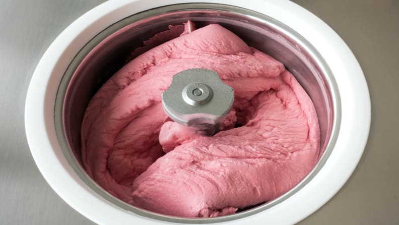 Homemade raspberry ice cream churning in a small professional ice cream machine.