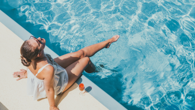 Woman sitting on the edge of a pool, legs in the water