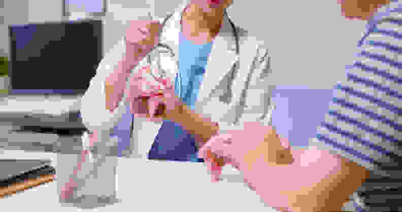 Closeup of a doctor in a white coat explaining brain model to an older man at a clinic