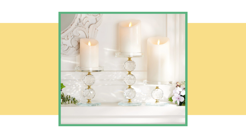An image of three crystal candle pedestals holding white votives on top of a cream mantle.