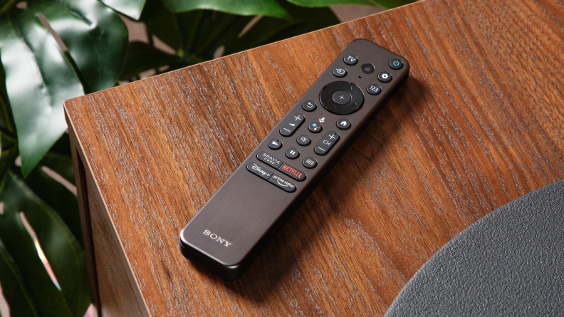 The Sony A95K remote sits on a wooden side table.