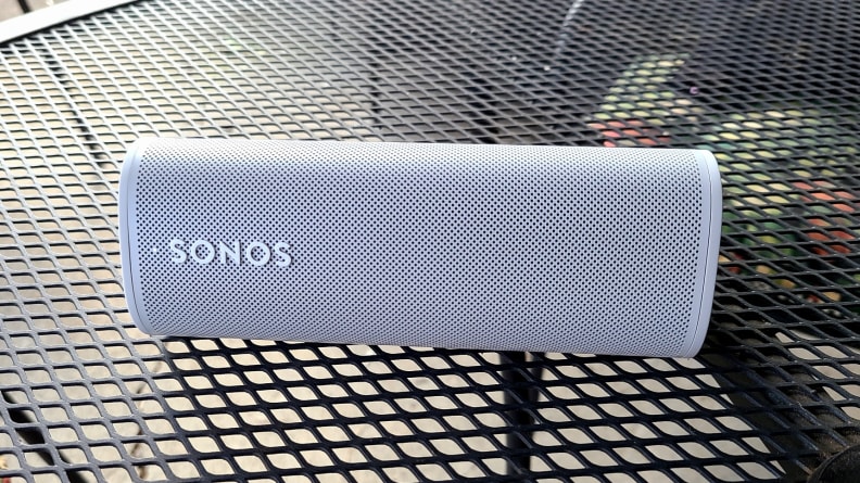 The white and tubular Sonos Roam set on a mesh metal table