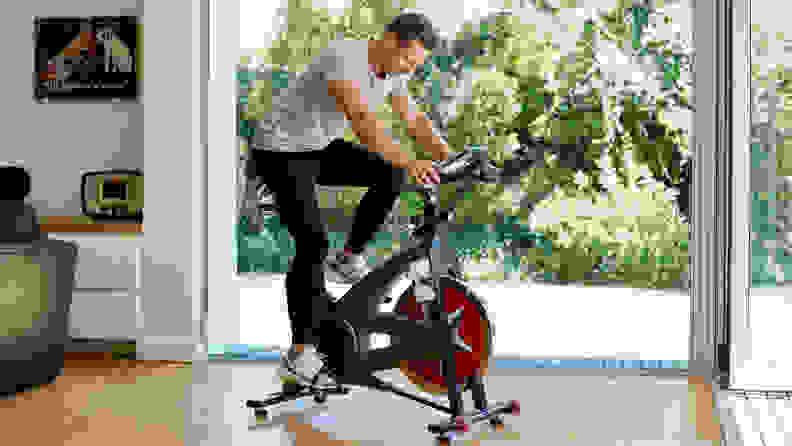 Full length of man working out on exercise bike at home