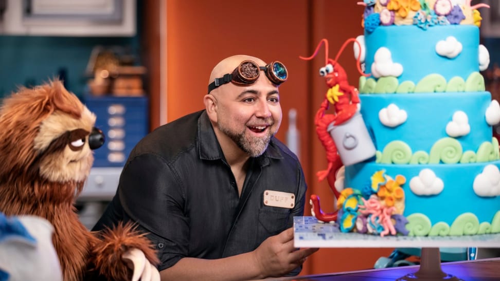 Celebrity chef Duff Goldman looking at a cake while standing near a muppet