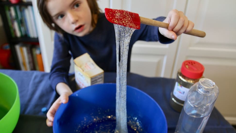 Little boy looking on in awe as he mixes slime made from Elmer's Glue and contact solution.