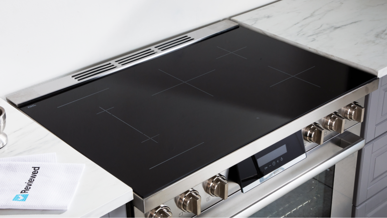The range's glass cooktop surrounded by a marble countertop
