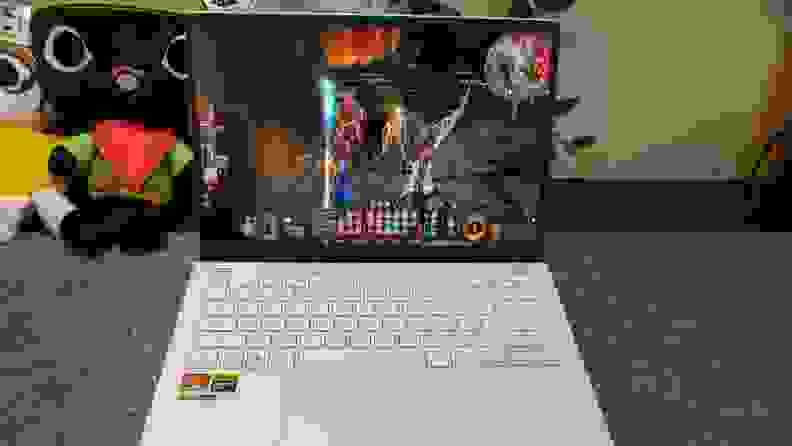 An open and powered on white laptop on a gray surface with objects in the background