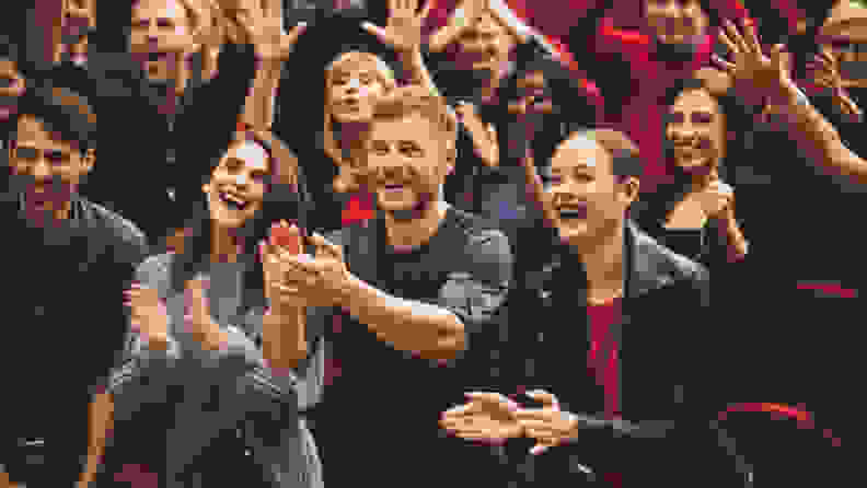 Group of excited people clapping hands in the theater.