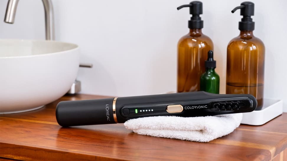 The black L'Oréal Colorsonic device lays on a sink basin.
