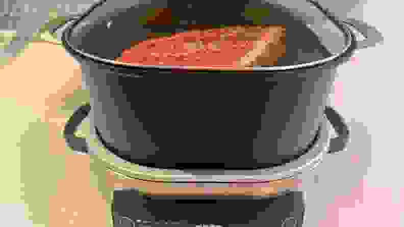 A raw chuck roast being slowly cooked inside of the Ninja Foodi PossibleCooker's 6-quart pot.