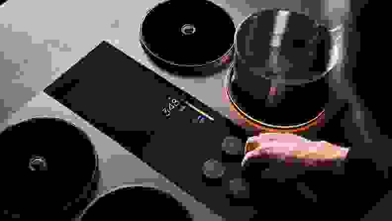 Close-up of a hand adjusting a knob on the Impulse Induction cooktop.