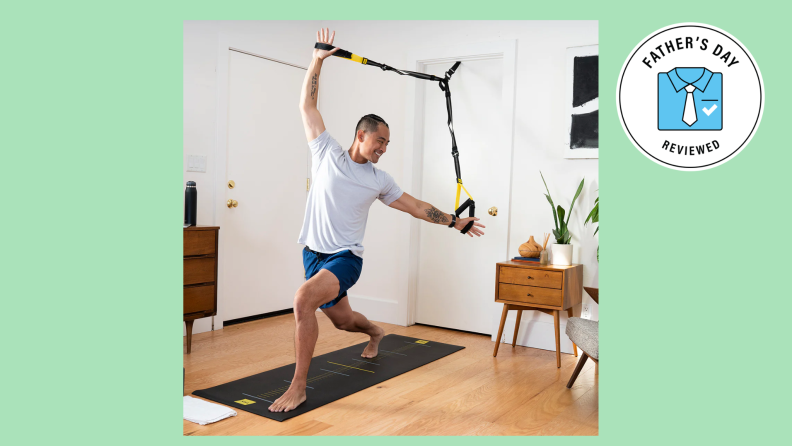 A man practices yoga using his TRX in a doorframe.
