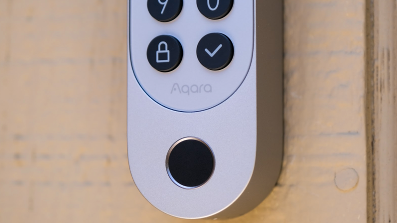 An upclose shot of the silver Aqara U200 smart lock keypad hanging on a light brown door