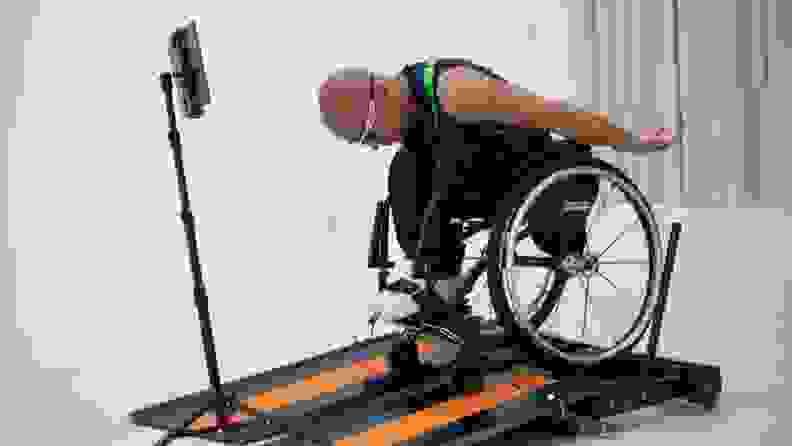 A man in a wheelchair lurches forward while using the Kangsters Wheely-X wheelchair treadmill.