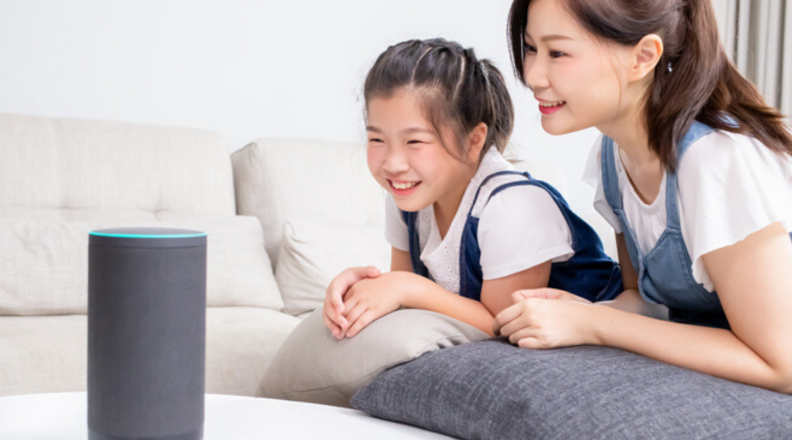 A mom and daughter talk to an Amazon Echo speaker.