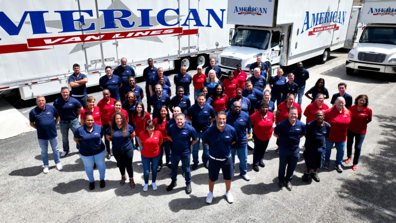 A group of people stand in front of a moving truck