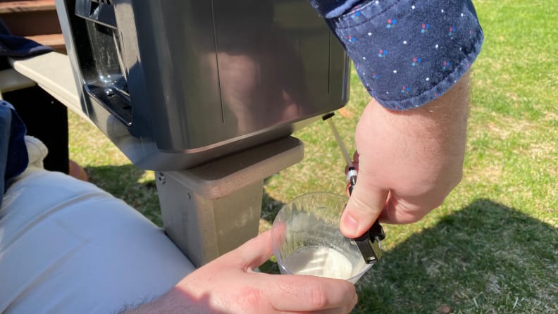 A person is trying to pour some beer from a dispenser. The beer seemed a bit foamy.