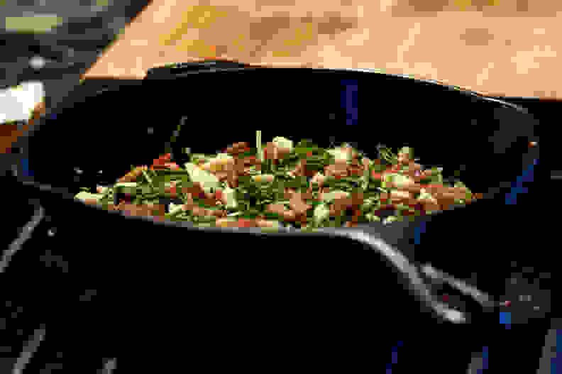 A cast-iron pan filled with food sits on a stovetop.