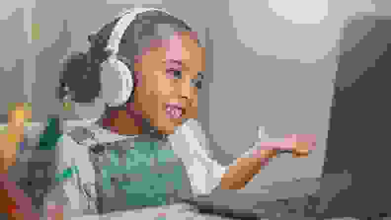 A child with headphones looking at a laptop.