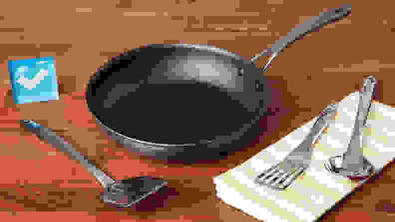 The Circulon ScratchDefense Nonstick Frying Pan next to metal utensils on a napkin.