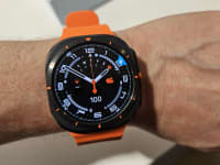 Person wearing the Samsung Galaxy Watch Ultra on their wrist with a neon orange band.