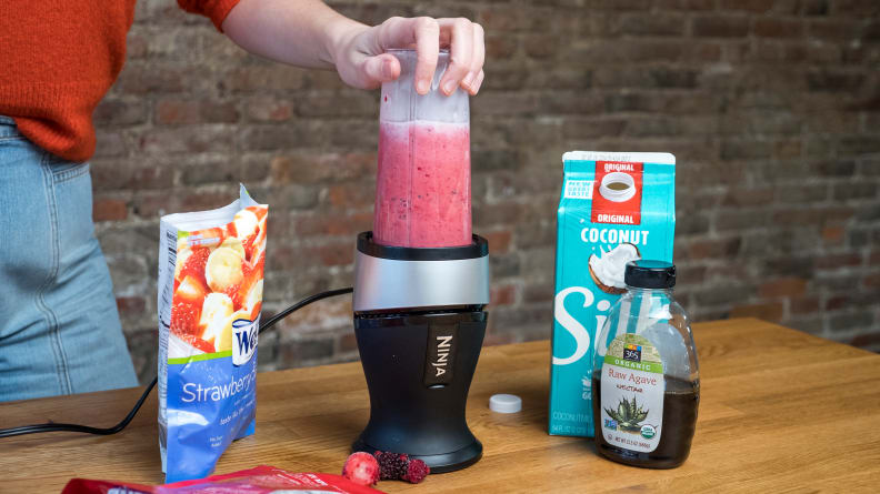 Our tester is making a smoothie in Ninja Fit, using syrup, nut milk, and frozen fruit.
