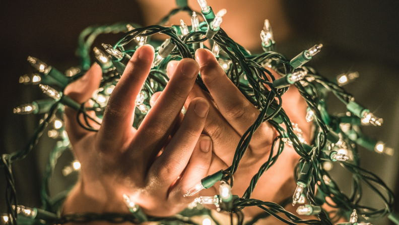 Illuminated white string lights are sitting in a person's two cupped hands
