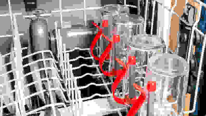 A close-up of the GE GDF630PSMSS dishwasher's upper rack, which shows off its bright red bottle jets. Glasses and dishes are loaded in for scale.