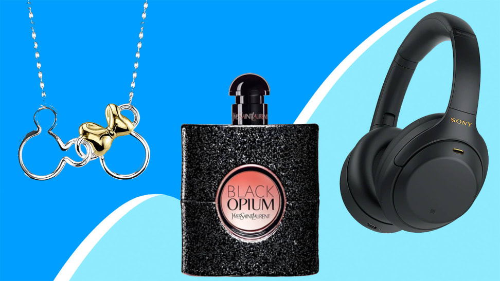 Gold plated necklace, black/pink perfume bottle and black wireless headphones on a blue swirl background