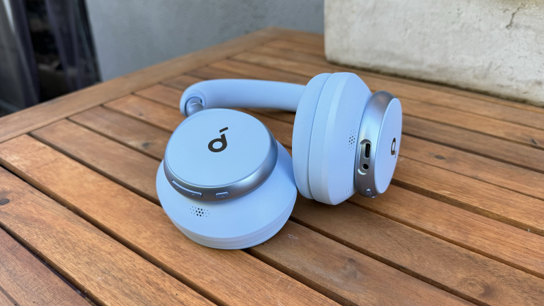 The powder blue Anker Soundcore Space One headphones on a wooden outdoor table.
