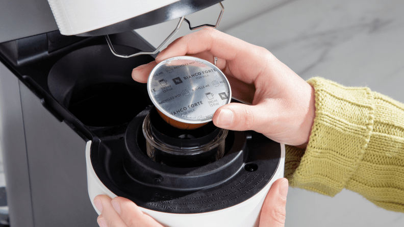 Person placing coffee pod into chamber on the Nespresso Vertuo Next coffee maker.