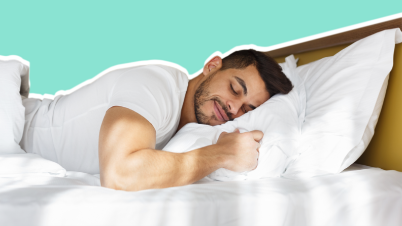 A man wearing a white shirt sleeps on a white bed and pillow, set against an aqua background.
