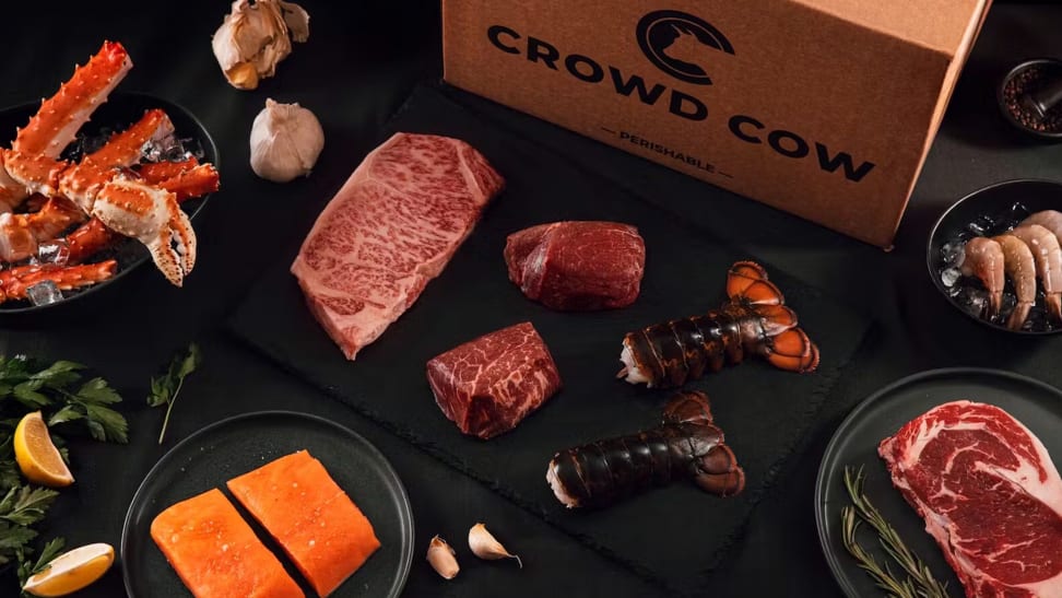 A collection of beef and shellfish from a Crowd Cow package on a black surface.