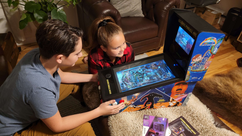 Two youngsters playing on a Legends Micro pinball machine.