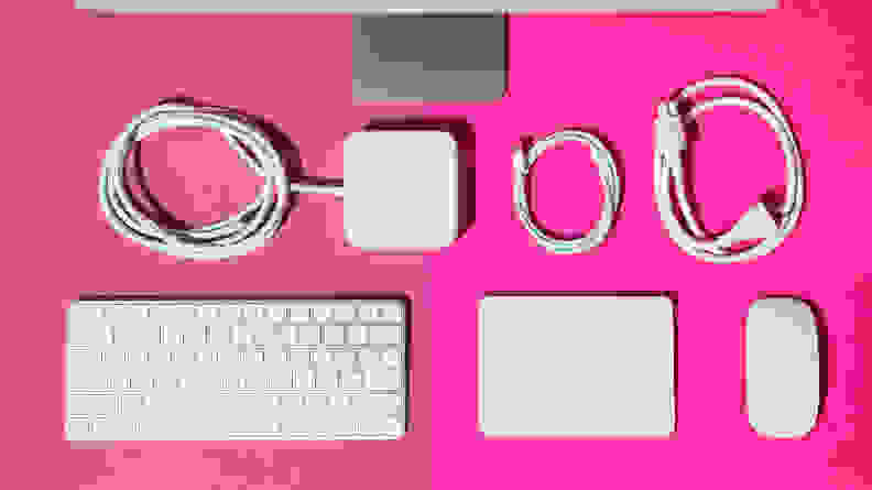 White computer peripherals arranged in a grid-like fashion on a hot pink background.