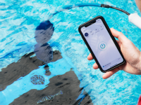 Dolphin Nautilus CC Plus Wi-Fi robot pool vacuum in a swimming pool with a person holding a smartphone showing the app in the foreground.