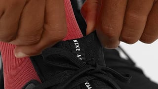 Close-up of a runner's hands lacing up a Nike running shoe.