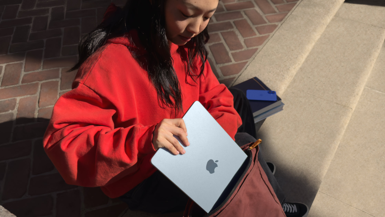 Student putting a MacBook Air 13 M4 in her backpack