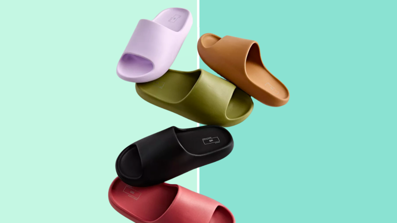 An image of several different colorways of the same wide plastic slide sandal, including a black sandal, a purple sandal, a green sandal, and a red sandal.