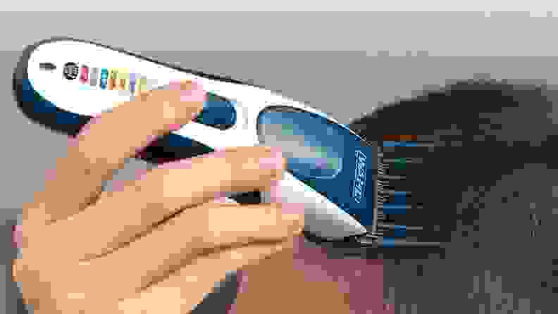 A person shaves their head with electric clippers.