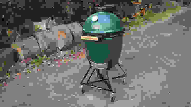 A Big Green Egg, closed, sitting outside on the cement.