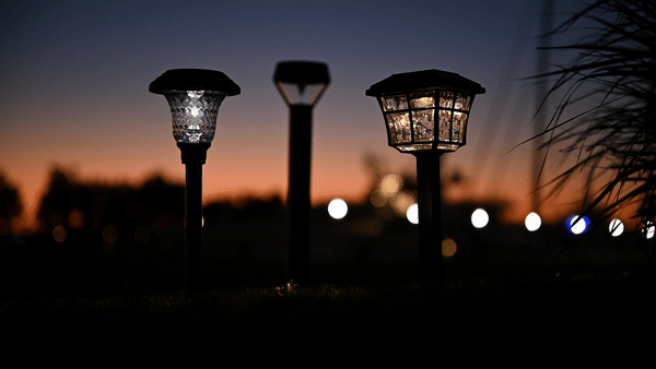 Three outdoor solar lights appear in a dark outdoor scene—the center light flicks on and off.