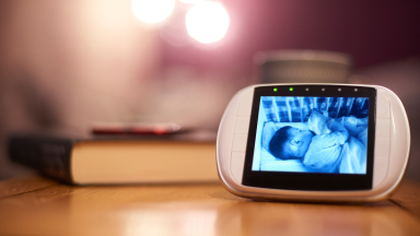 A baby monitor on a nightstand displaying a sleeping baby