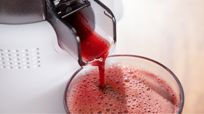 The juicer pouring juice onto a glass.