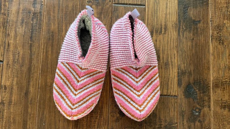 Two pink Bombas gripper slippers on hardwood floor.