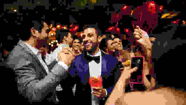 A man wearing a royal blue tuxedo shaking hands with someone during a party.