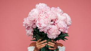 Woman holding bouquet of pink flowers in front of her face