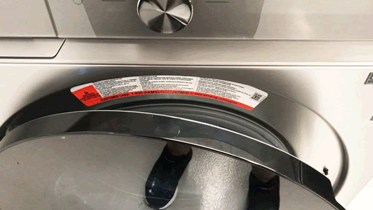 Moving gif of someone using hand to close the washer door on the Samsung WF53BB8700AT, which still reveals the machine's warning label.