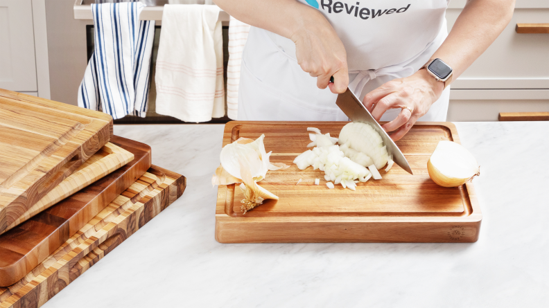 Person chopping onion on wooden cutting board